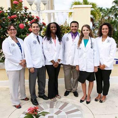Group of doctors standing in front of flowers and palm trees