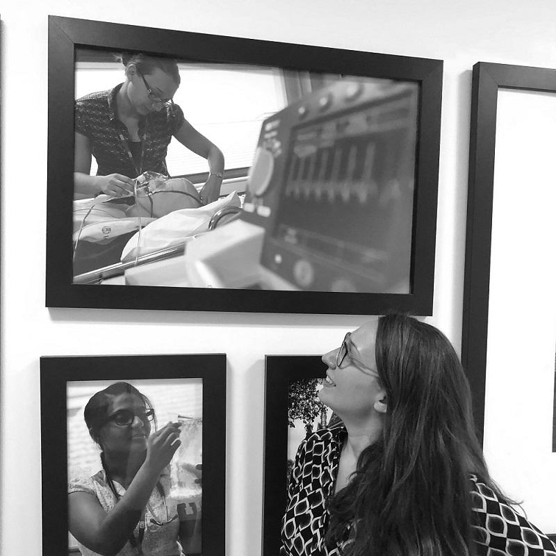 A doctor looks at a photo of herself on the wall
