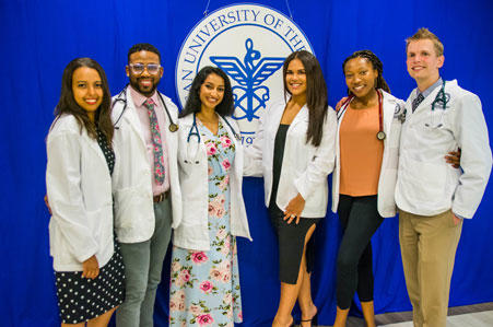 Group photo in white coats in front of AUC seal