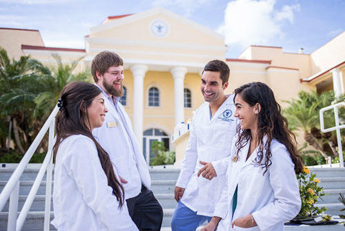 Students in white coats in front of school